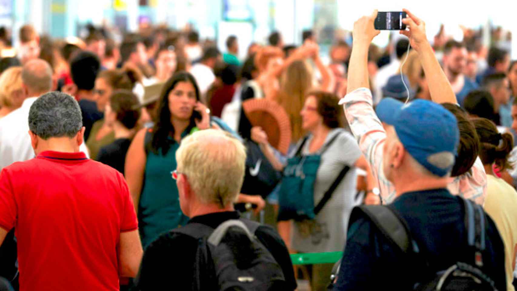 Un pasajero hace fotografías de las colas en los controles de seguridad de Barcelona-El Prat / EFE