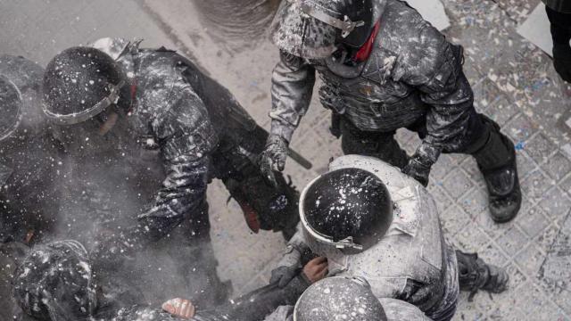 Los Mossos d’Esquadra llenos de harina por parte de las personas que han intentado paralizar el desahucio de una familia por impago de alquiler en el barrio de Poble Sec / PAU VENTEO - EUROPA PRESS