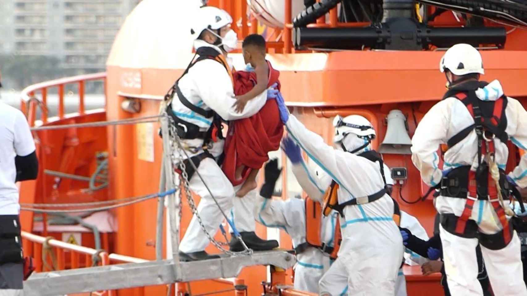 Un miembro de la Cruz Roja ayuda a bajar del barco a un niño: Cataluña acoge a 43 jóvenes inmigrantes / EP