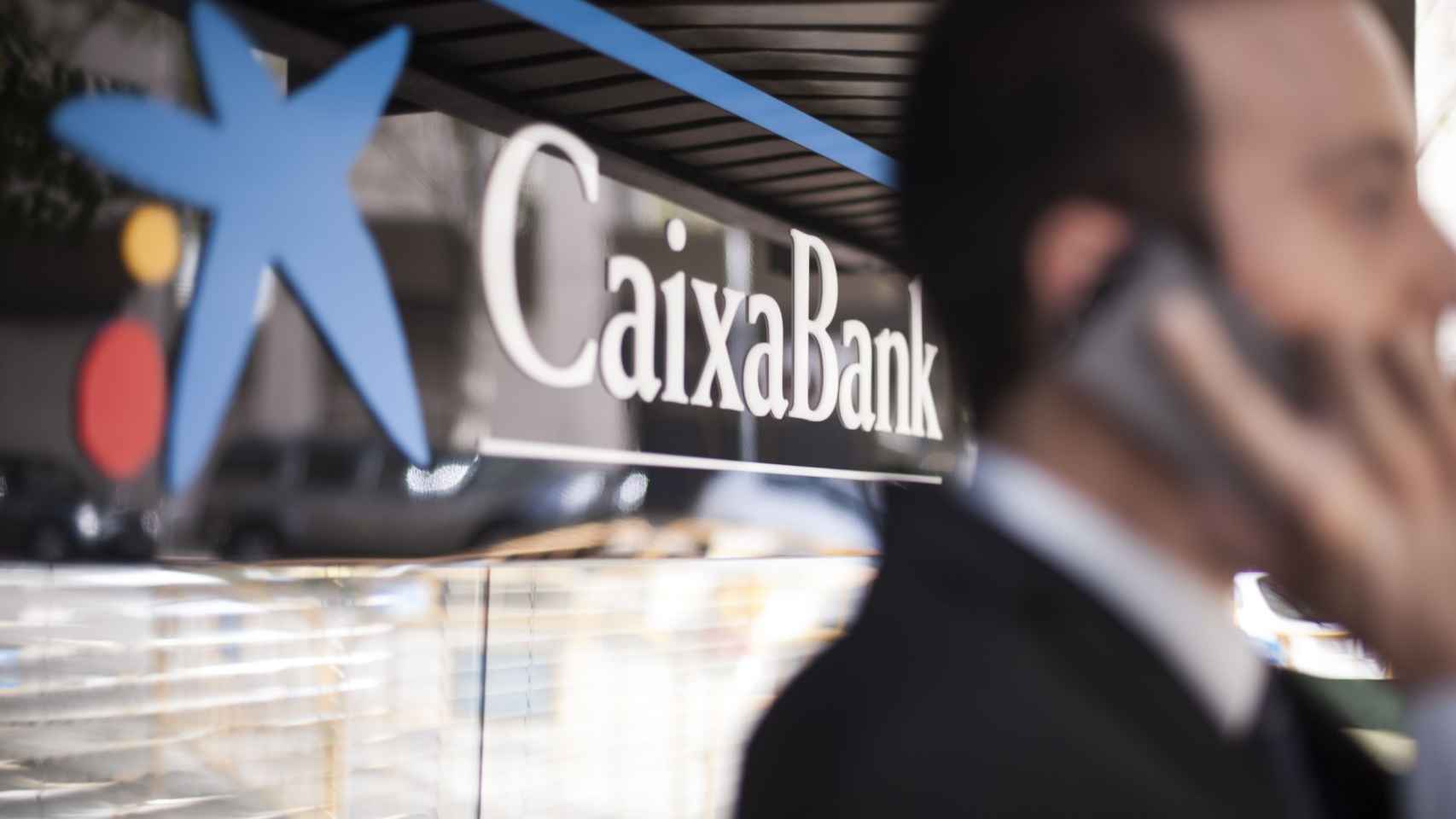 Un hombre habla por el móvil en una sucursal de CaixaBank  / CG