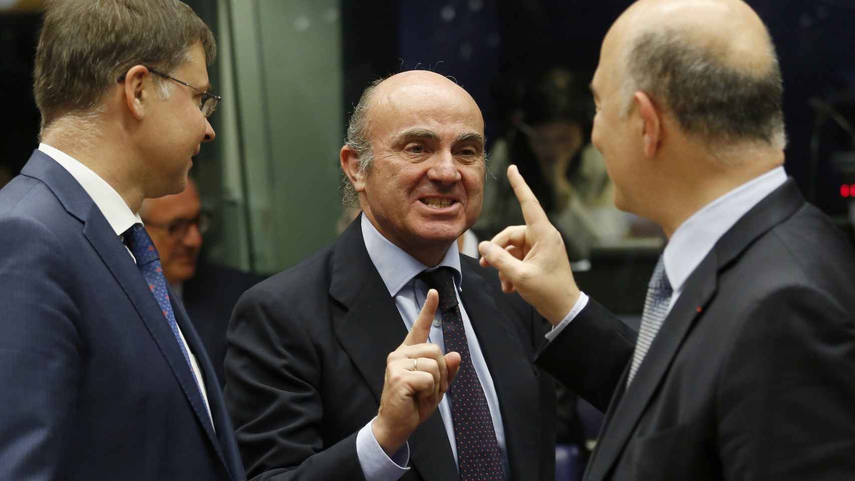 Luis de Guindos (c), conversa ayer con el comisario europeo de Asuntos Económicos, Pierre Moscovici (d), en presencia del vicepresidente de la CE para el Euro y el Diálogo Social, Valdis Dombrovskis (i) / EFE