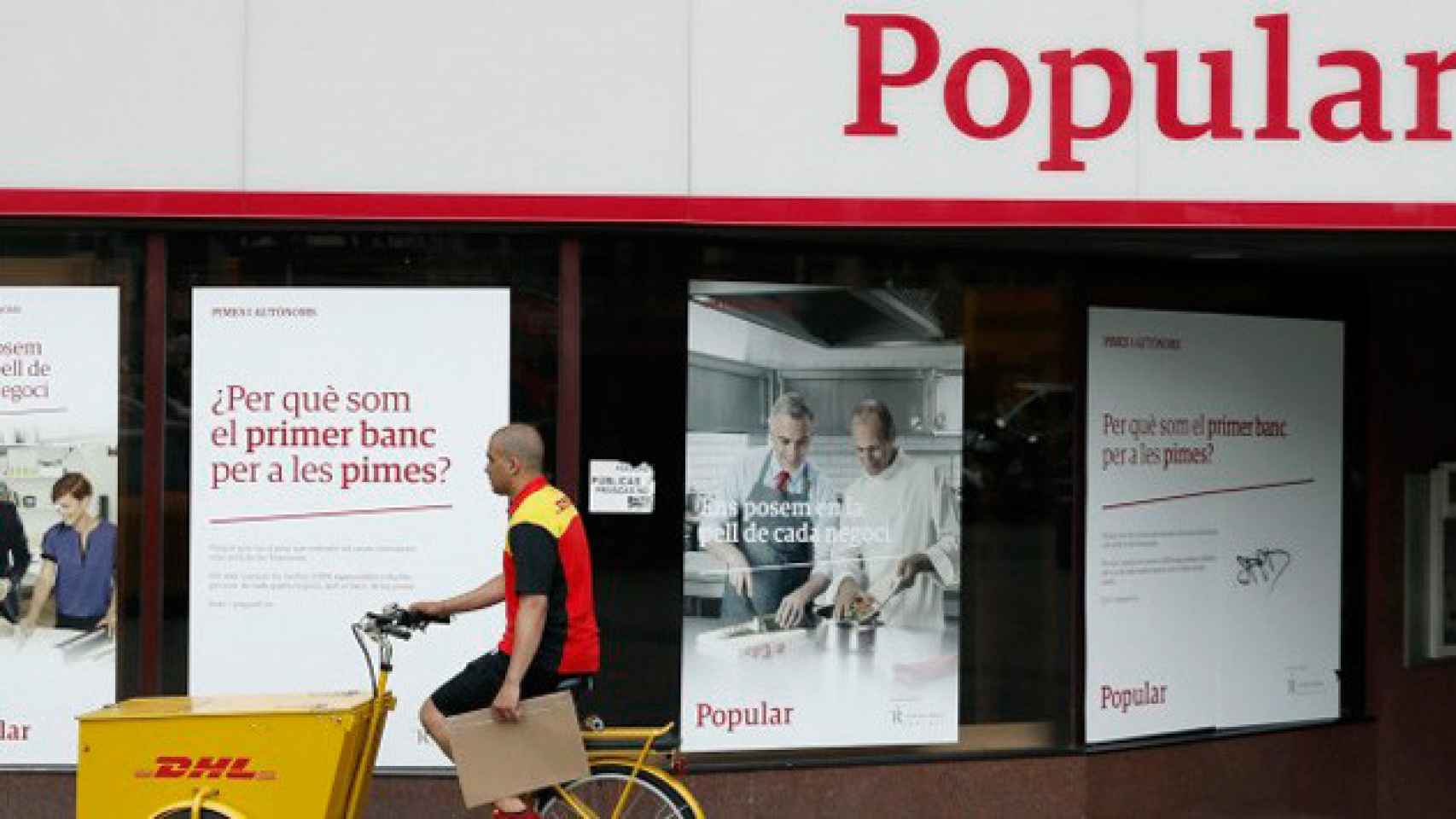 Un repartidor pasa por delante de una oficina del Banco Popular en Barcelona / CG