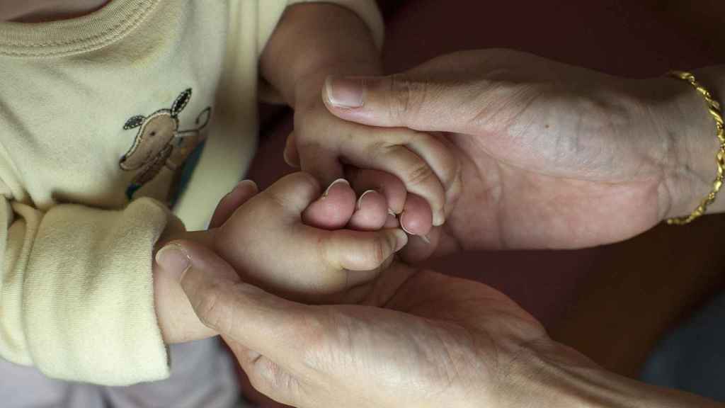 Una madre y su hija, cogidas de las manos / CG