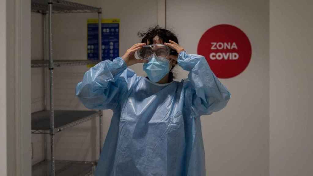 Una sanitaria se viste con un EPI en la zona Covid de Vall de Hebron