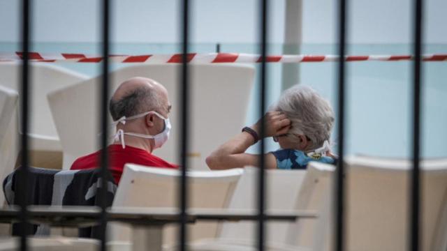 Una pareja con mascarilla en la piscina de un hotel en Tenerife en cuarentena por el coronavirus / EP