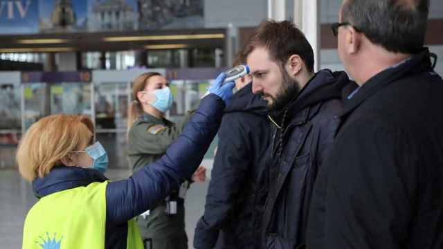 Personal de un aeropuerto toma la temperatura a los viajeros ante el brote de coronavirus / EFE