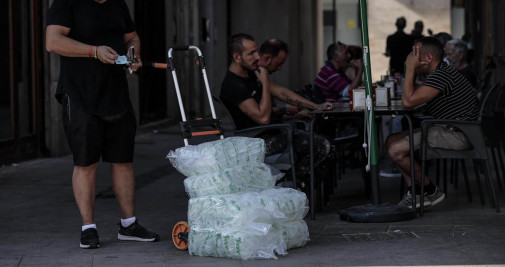 Un repartidor lleva una carretilla cargada con bolsas de hielo a un bar este jueves en Valencia - EFE/Ana Escobar