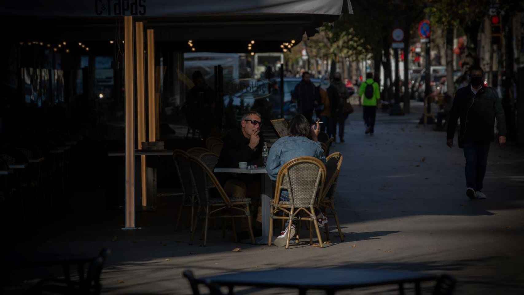 Un hombre y una mujer fuman en la terraza de un bar / EP