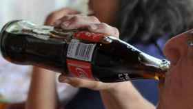 Un joven bebe Coca-Cola del tradicional botellín de cristal /  EFE