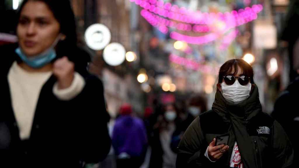 Personas pasean por la calle con y sin mascarilla / EFE