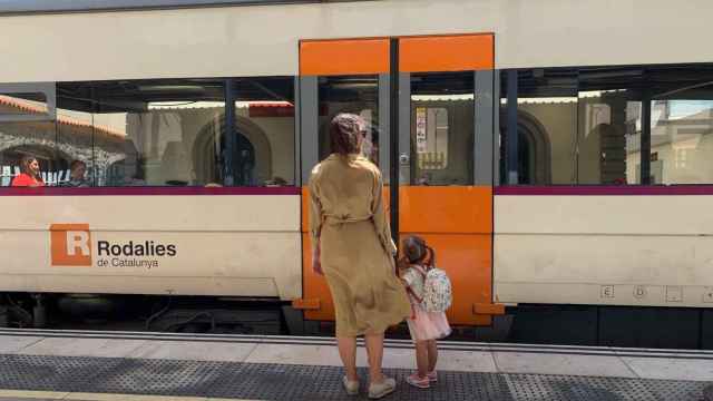 Una mujer y una niña frente a un tren de Rodalies Renfe / EP