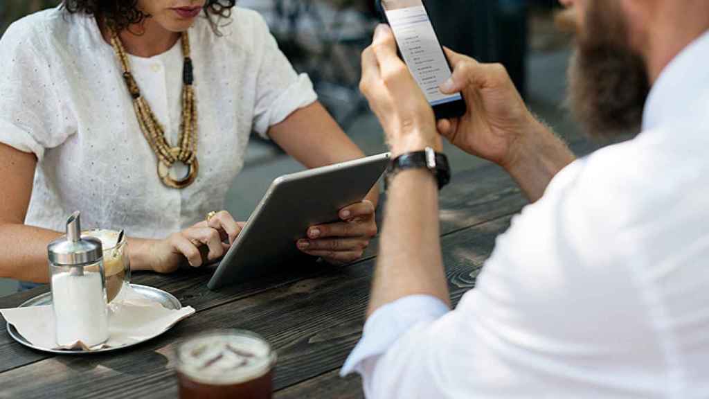 Una pareja consultando sus dispositivos móviles