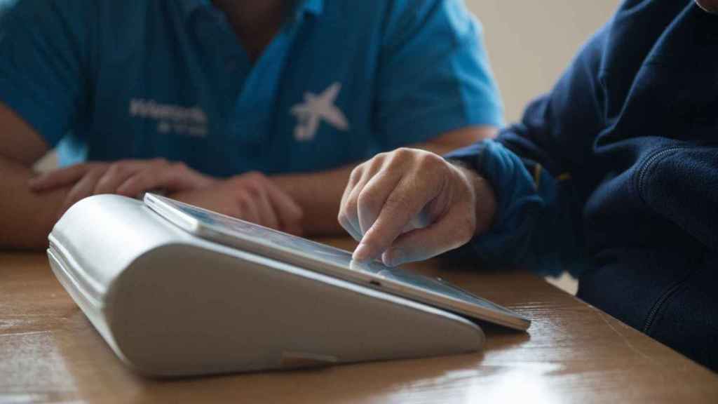 Voluntaria de La Caixa enseña a una persona el uso de tablets para comunicarse con sus familiares /LA CAIXA