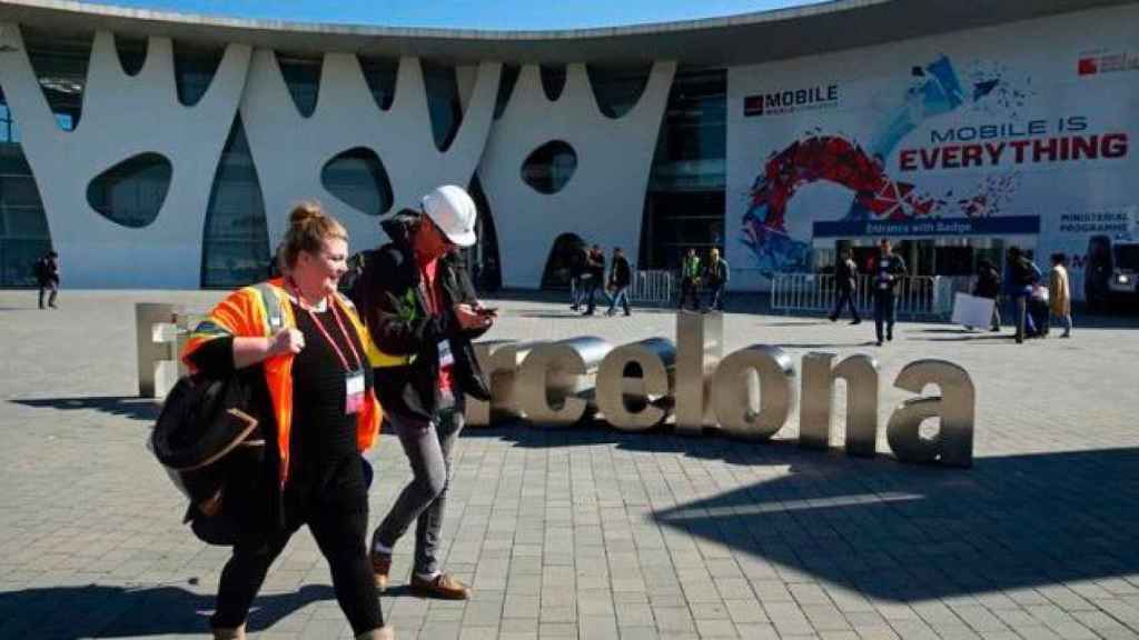 Dos congresistas pasean por la puerta de entrada al MWC en el recinto de la Fira de Barcelona / EFE