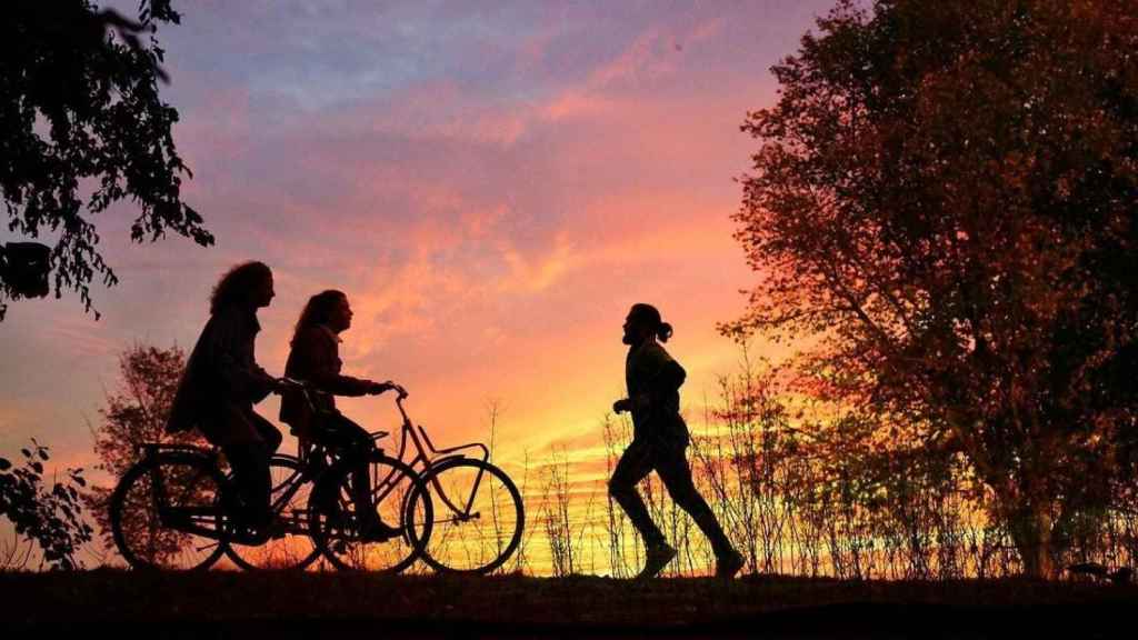 Escena donde se ve a un hombre correr y a dos mujeres en bicicleta al atardecer / Mabel Amber EN PIXABAY