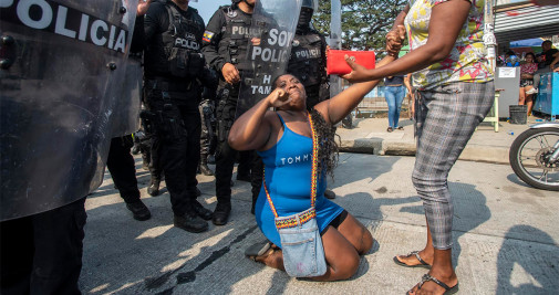 Policías vigilan a familiares que esperan información de los presos heridos a las afueras de la penitenciaría Litoral donde se presentó una nueva riña entre policías y reos y que deja hasta ahora 10 heridos, hoy en Guayaquil (Ecuador) - EFE/Mauricio Torres