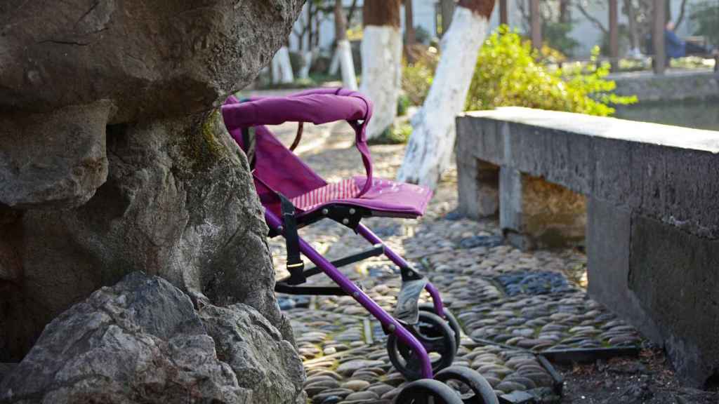 Un cochecito de bebé detrás de un árbol en un parque / CG