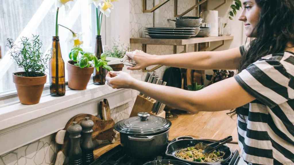 Mujer podando una planta mientras cocina