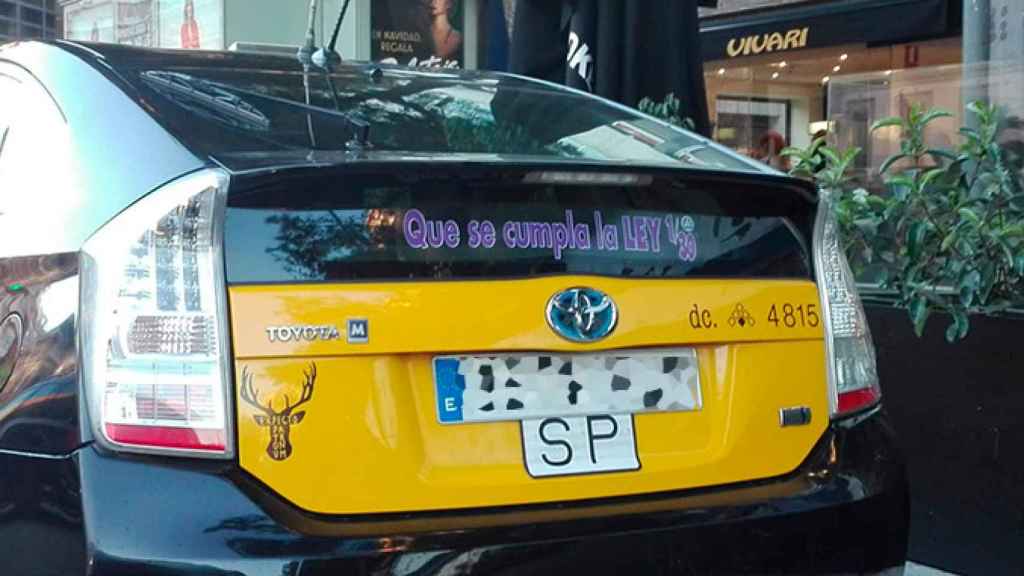 Un taxi con una pegatina con la leyenda Que se cumpla la ley 1/30 de las VTC / CG