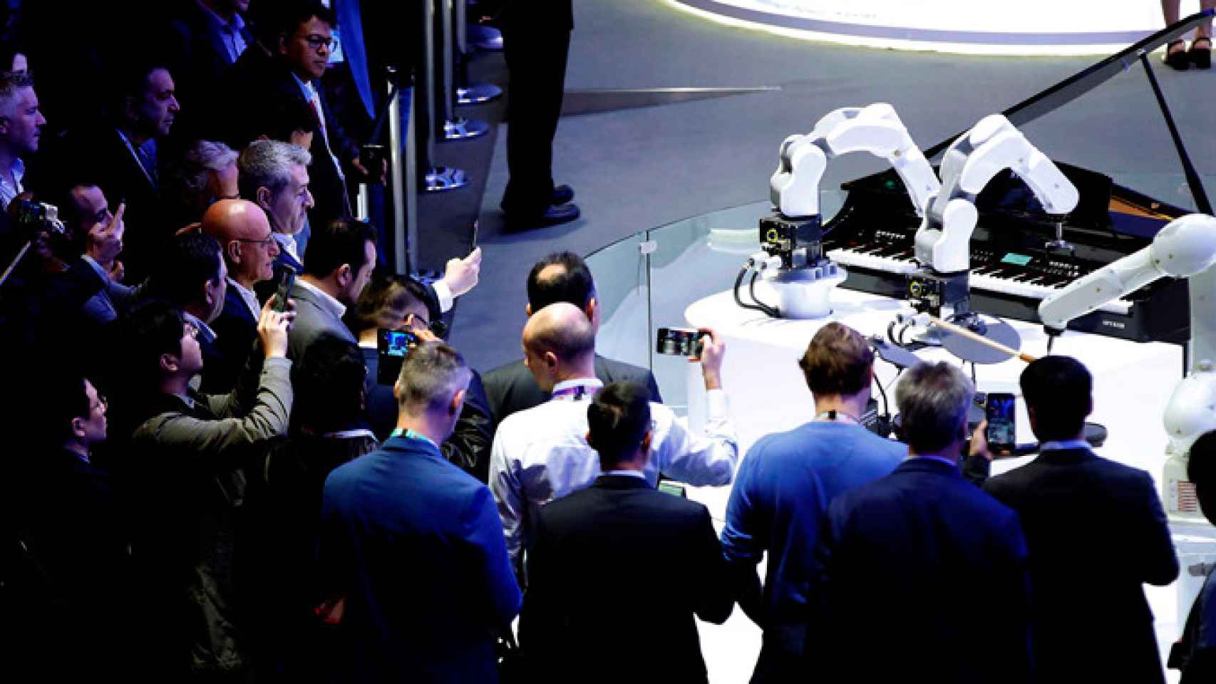 Numerosos visitantes graban y fotografían dos robots que tocan el piano y la batería en uno de los expositores de la XIX edición del Mobile World Congress / EFE