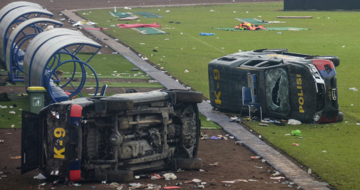 Una mujer pasa junto a un vehículo de la policía destrozado tras los disturbios en un partido de fútbol en el estadio Kanjuruhan de Malang / EFE - Sandi Sadewa