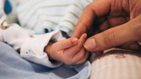 Una persona da la mano a un bebé / EP