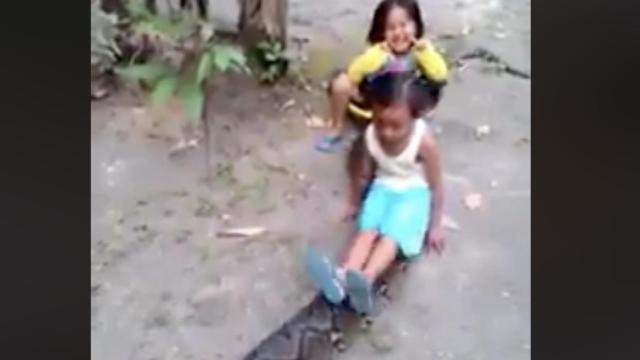Una foto de las menores encima de la serpiente mientras juegan / Facebook