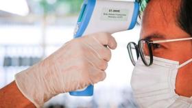 Un sanitario toma la temperatura a un paciente en pleno brote de coronavirus / EFE