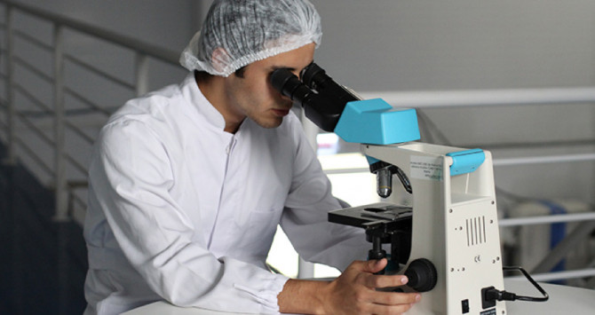 Un hombre busca eosinófilos con el microscopio de un laboratorio
