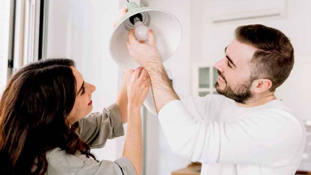 Una pareja cambiando una bombilla por una de bajo consumo / CG