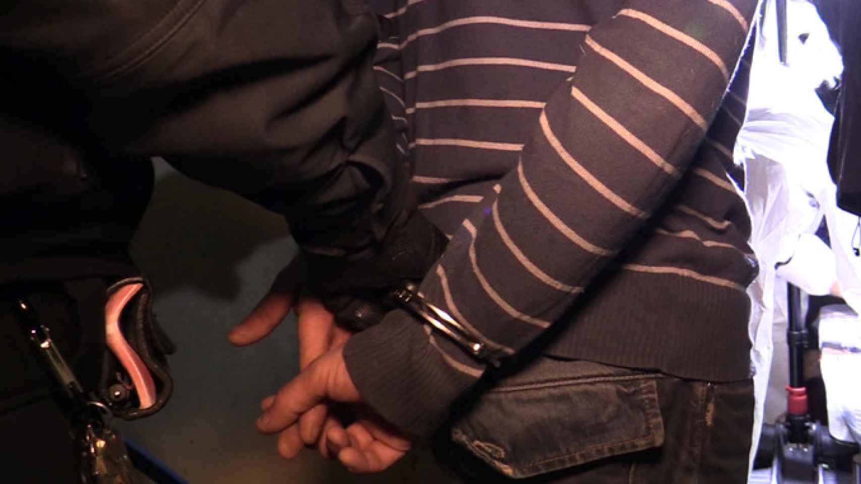 Un mosso conduce al hombre detenido por agresión sexual y robo con violencia a dos ancianas en Barcelona fuera de su casa / MOSSOS