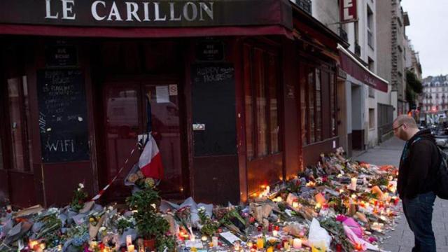 Un parisino observa las flores despositadas ante uno de los restaurantes que fueron objetivo de los terroristas.