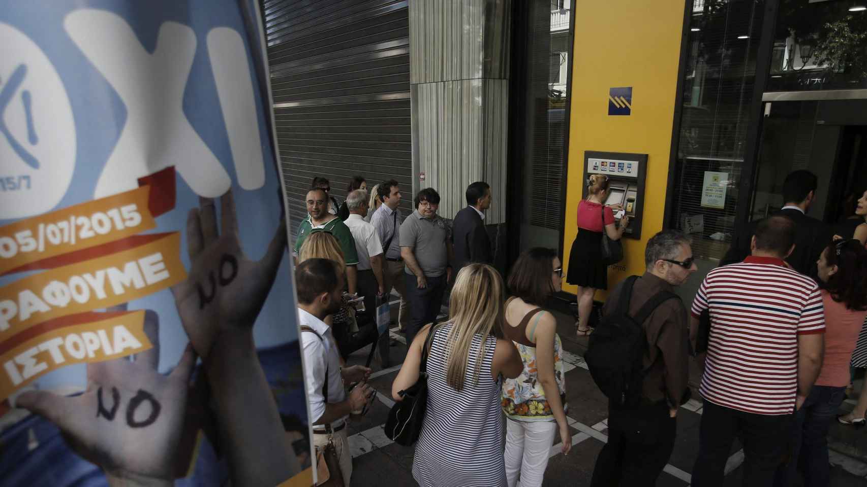 Las colas ante los cajeros se hacen más largas cada día. En la imagen aparece en primer término un cartel animando al 'no' en el referéndum