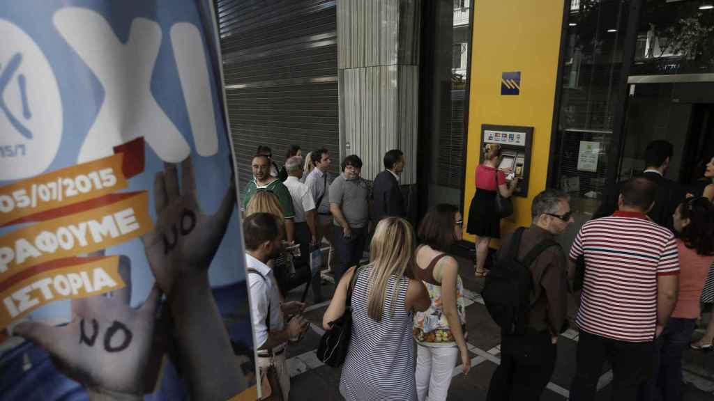 Las colas ante los cajeros se hacen más largas cada día. En la imagen aparece en primer término un cartel animando al 'no' en el referéndum