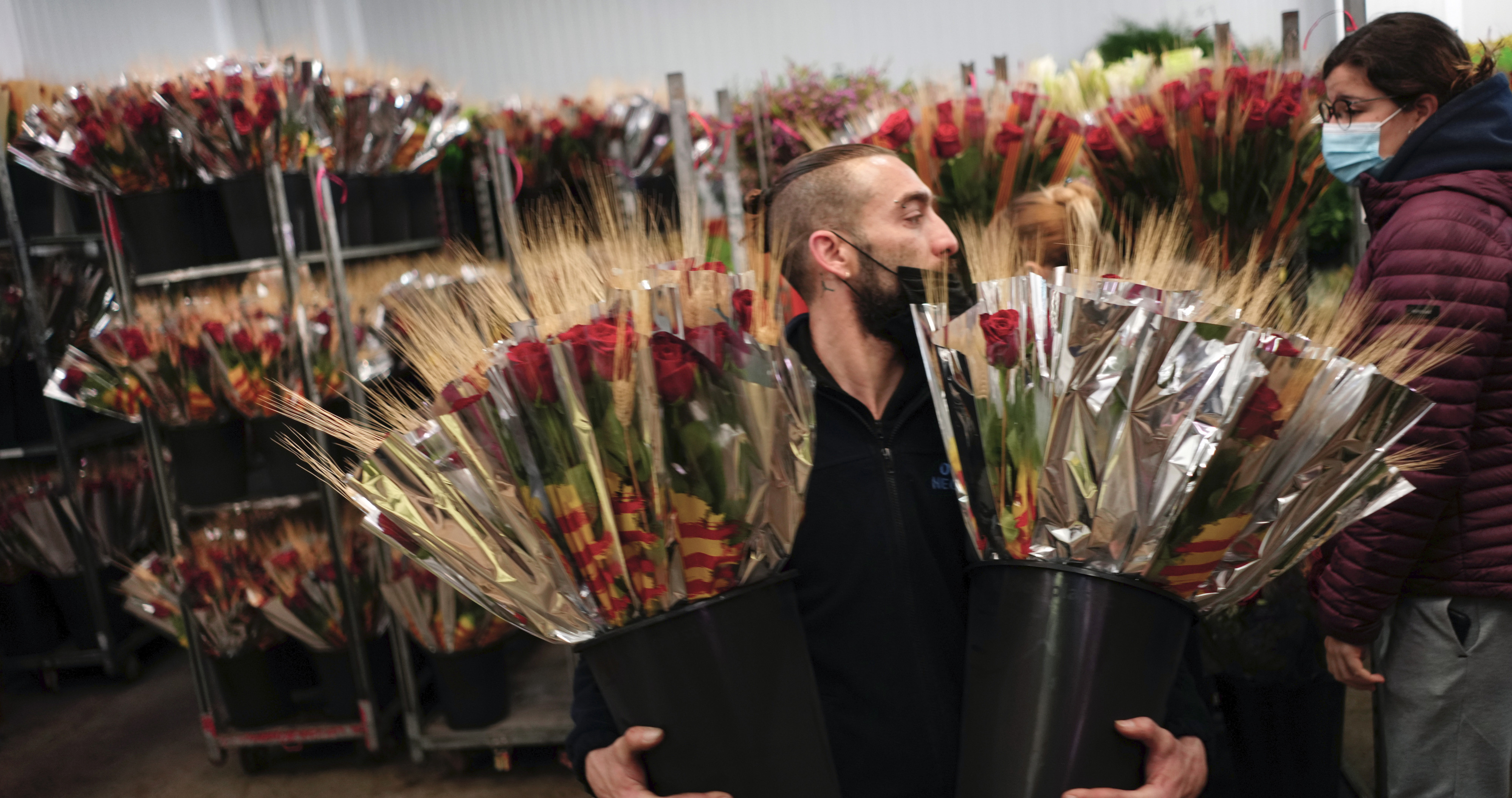 Un florista transporta varias decenas de rosas este jueves en Mercabarna-Flor donde trabajan a buen ritmo para la diada de Sant Jordi de este próximo sábado / EFE