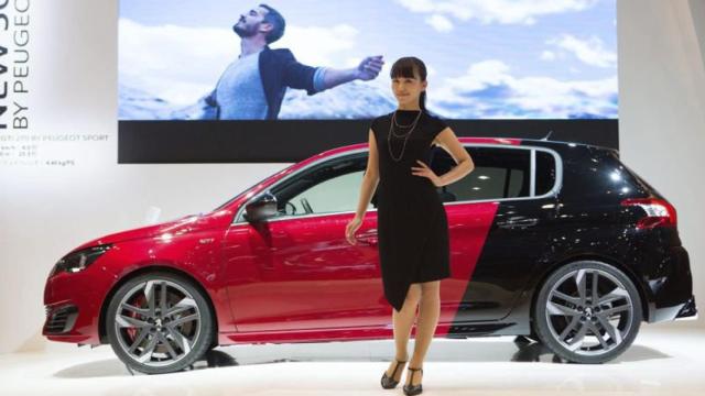 Una azafata posa junto al nuevo Peugeot 308 GTi by Peugeot Sport durante su presentación en el Salón del Automóvil de Tokio.