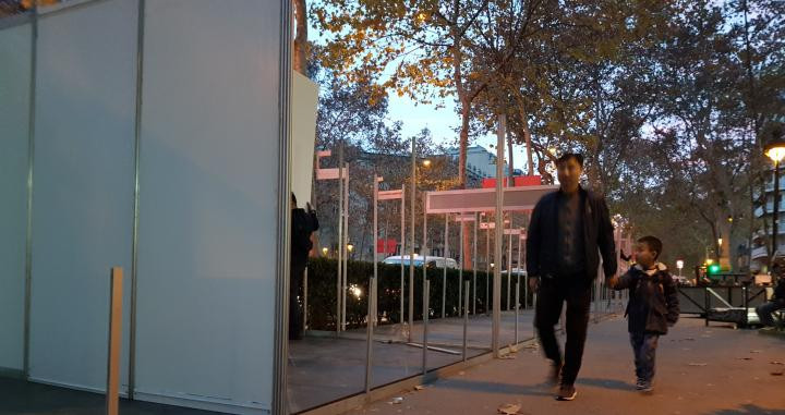 Un padre y un hijo pasan por delante de la Feria de Santo Tomás y Reyes de Barcelona en pleno montaje / CG