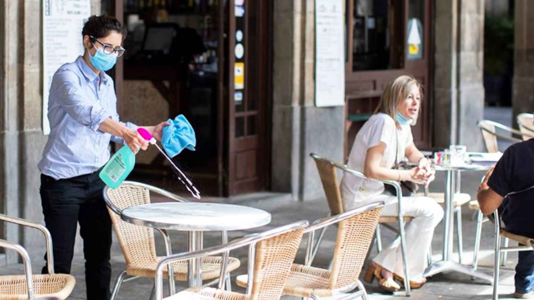 Imagen de una restauradora desinfectando una mesa en la Plaza Real de Barcelona / EFE