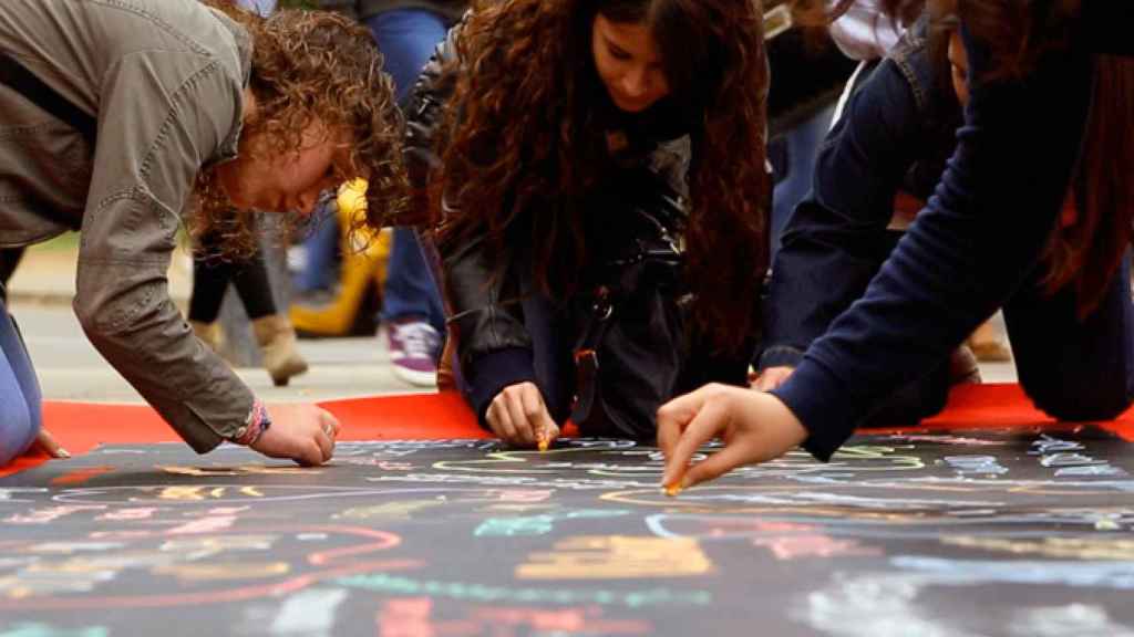 Imagen de cuatro alumnas pintando con tizas en la calle / PAU EDUCATION