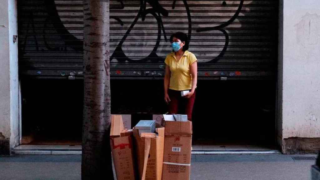 Una mujer observa la acumulación de basura enfrente de su establecimiento de Sant Andreu / PABLO MIRANZO