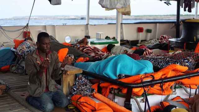 Un hombre reza en la cubierta del Open Arms, frente a la costa de Lampedusa / EFE