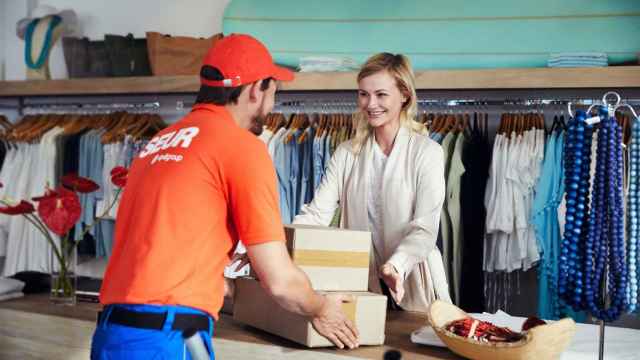 Un empleado de Seur entrega un paquete en una tienda de ropa / EP