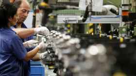 Dos operarios trabajando en una factoría de coches.