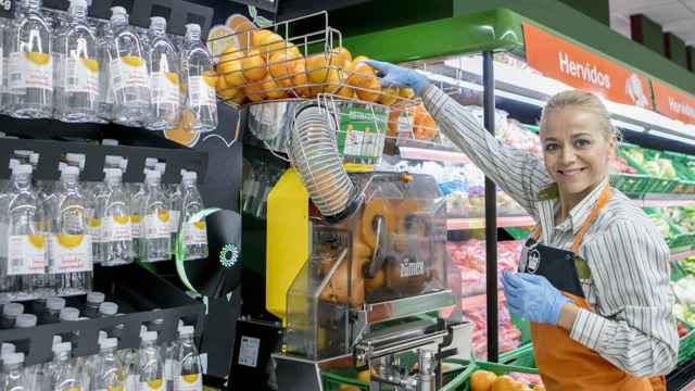 Una empleada de Mercadona muestra como funciona la maquina de zumo recién exprimido / EE