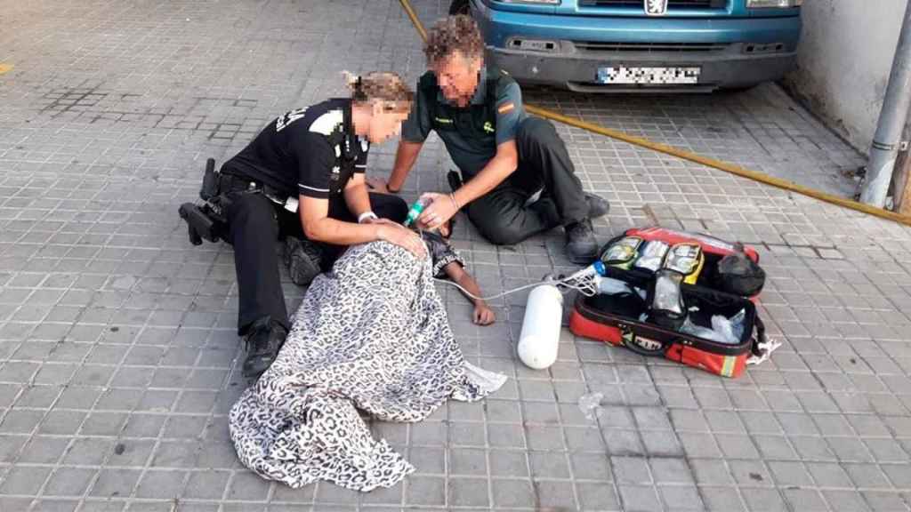 Dos agentes de la Guardia Civil atienden a un niño afectado por el incendio de un piso en Pineda de Mar / EP