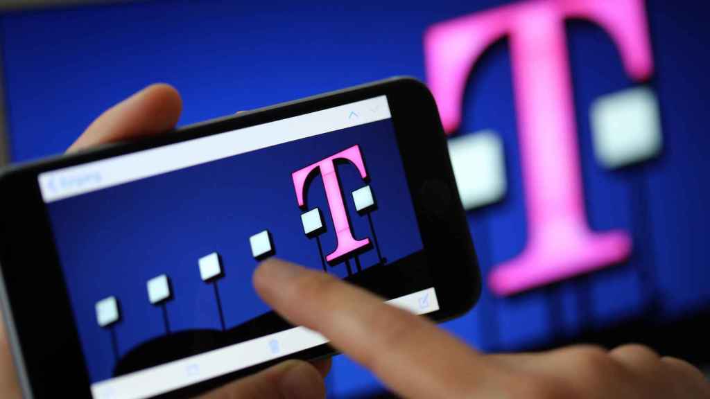 Una mujer mira en su móvil el logo de Deutsche Telekom / Oliver Berg - DPA - EUROPA PRESS