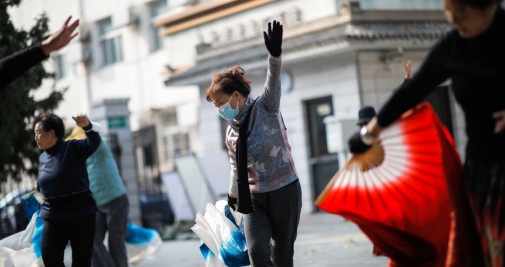Una mujer con mascarilla se ejercita en un parque de Pekín / EFE - WU HAO