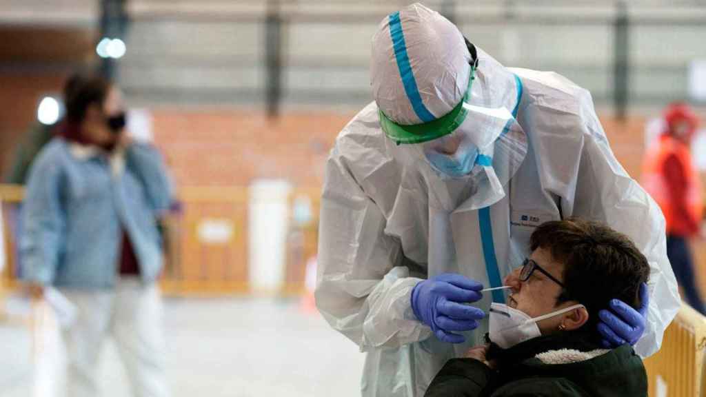 Imagen de un sanitario llevando a cabo un test PCR a una paciente, el sector en el que los recortes son alarmantes según Amnistía Internacional / EFE