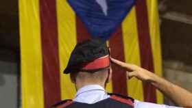 Un agente de Mossos frente a una bandera estelada, símbolo de los independentistas / TWITTER