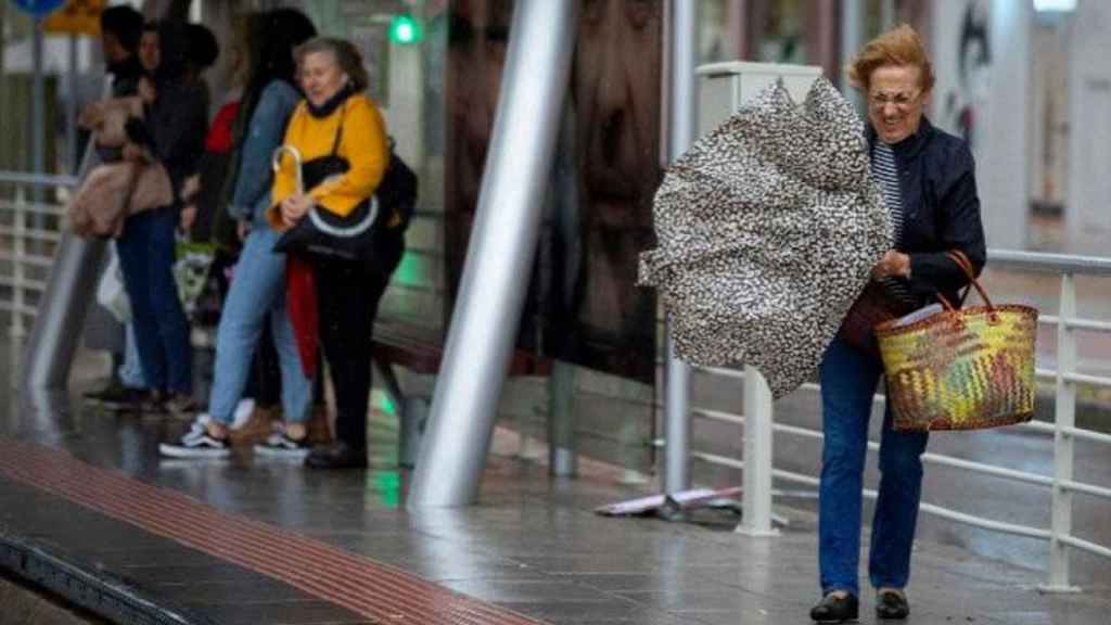 Una mujer lucha contra el viento que rompe su paraguas / EFE